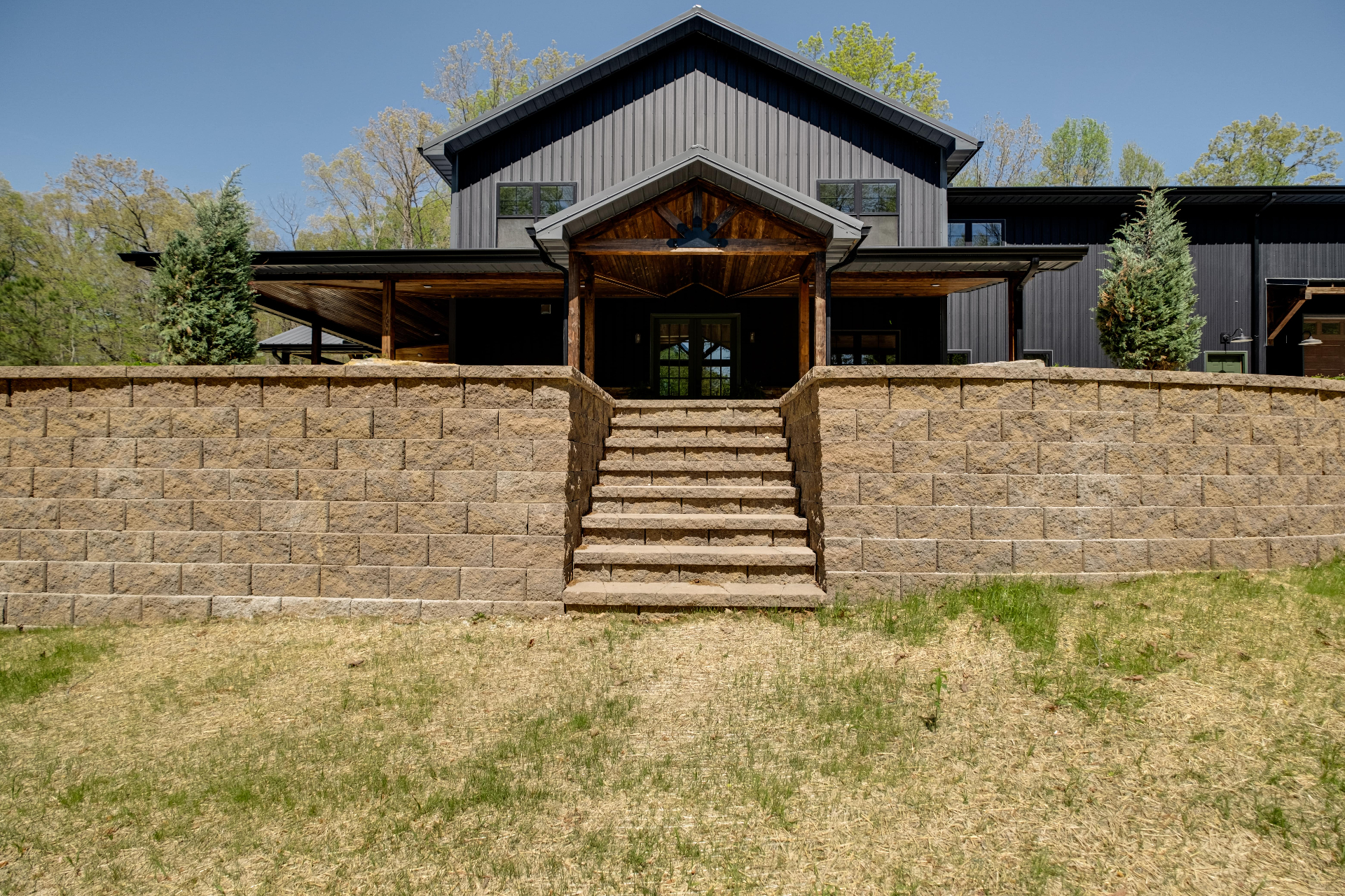 Custom retaining wall with stone stairs and covered porch at luxury Tennessee home by Prestige Landscape
