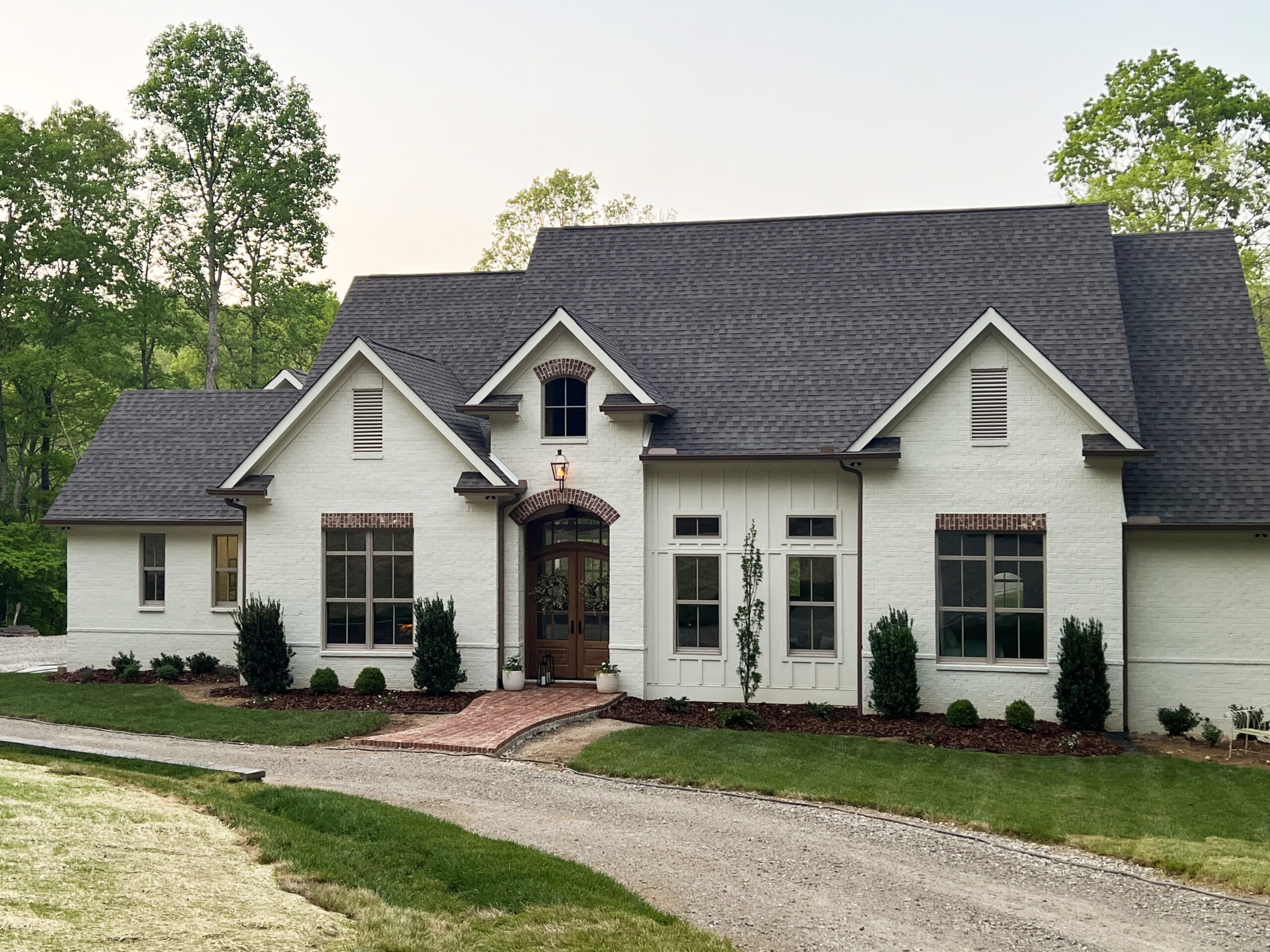 A high-end front yard landscape in Nashville, TN, showcasing mature trees, manicured lawns, and vibrant flower beds. This design enhances curb appeal and boosts property value